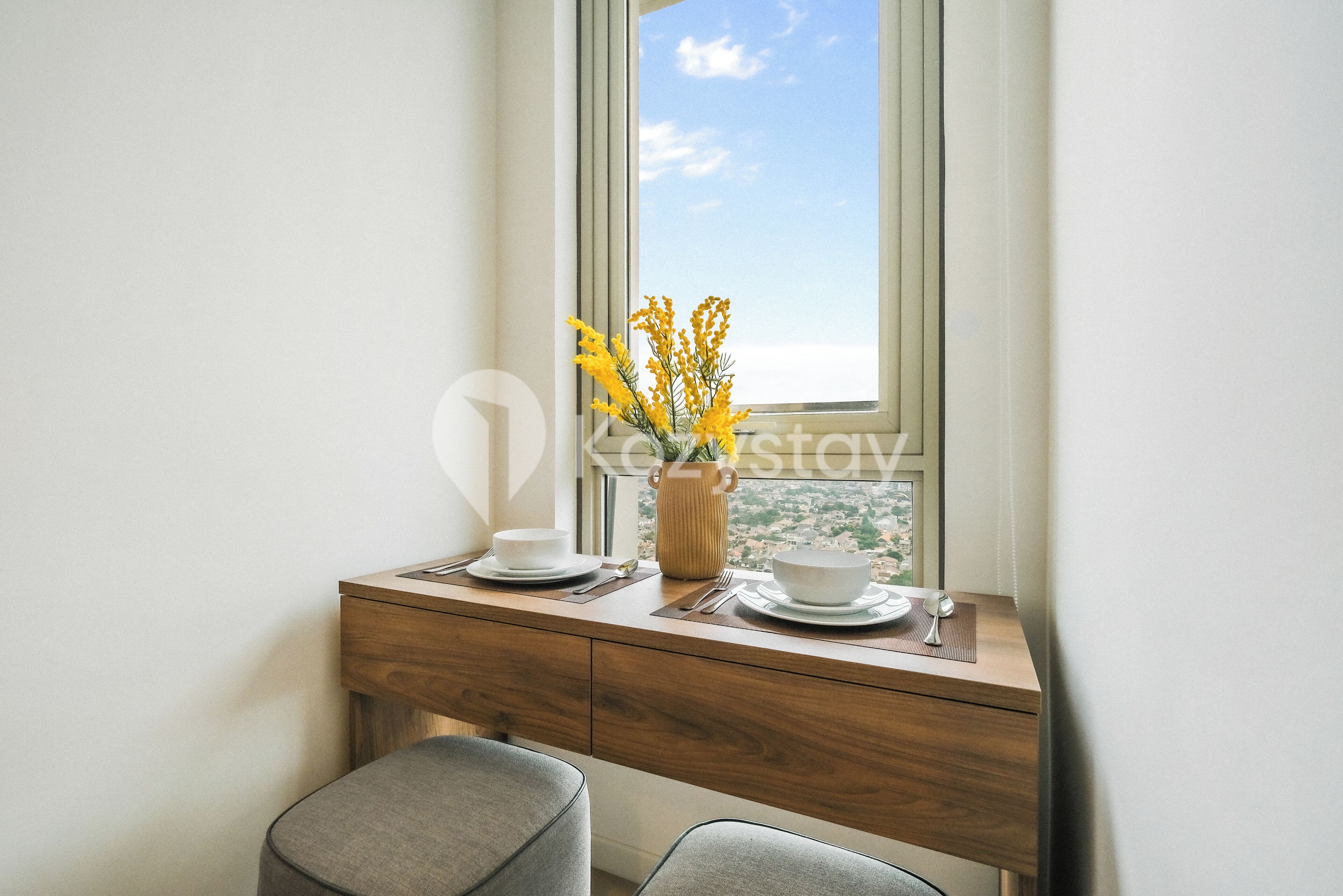 A wooden desk with a vase of yellow flowers, a cup, and a bowl.