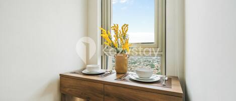 A wooden desk with a vase of yellow flowers, a cup, and a bowl.