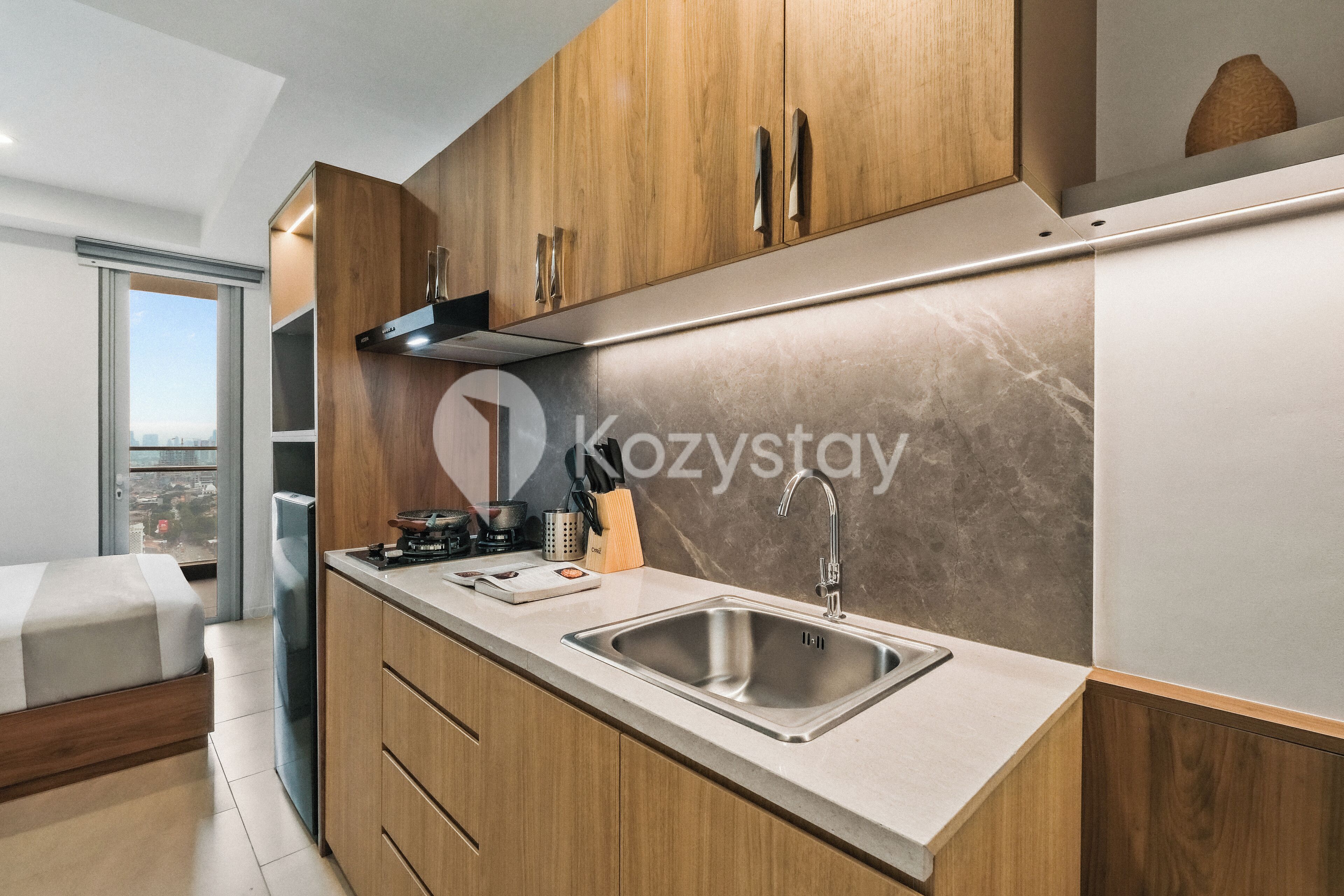 A modern kitchen with wooden cabinets, a stainless steel sink, and a large window offering a city view.