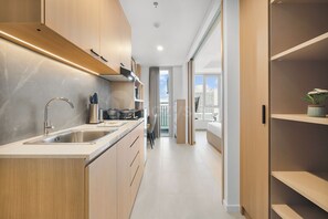 Eine moderne Küche mit einer Edelstahlspüle, Holzschränken und Blick auf die Stadt durch große Fenster.