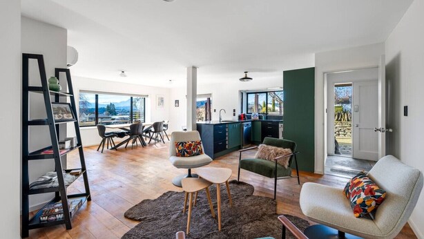 A spacious living area with a dining table, chairs, a sofa, and a bookshelf. - Wanaka close to town | Modern | Fireplace & Heatpumps | Sleeps 6 (Wānaka)