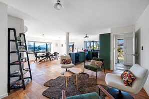Ein geräumiger Wohnbereich mit Esstisch, Stühlen, einer Couch und einem Bücherregal.