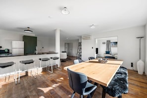 Una cocina moderna con una isla central, taburetes de bar y una mesa de comedor con sillas.