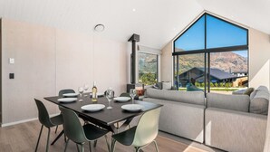 A modern dining area with a table set for four, a sofa, and a large window offering a mountain view.