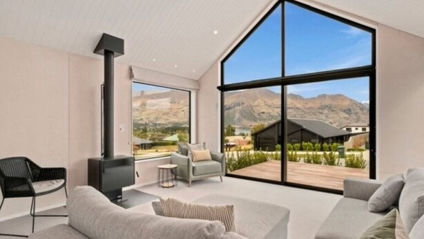 A spacious living room with a large window, a fireplace, and a view of a mountainous landscape.