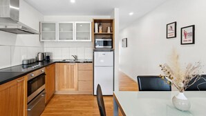 Una cocina moderna con gabinetes de madera, una campana extractora de acero inoxidable y un microondas integrado.
