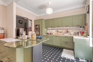 Una cocina con gabinetes verdes, encimera de mármol y alfombra con estampado blanco y negro.