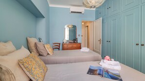 A bedroom with two beds, a dresser, a mirror, and a wardrobe.