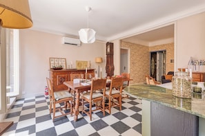 A dining area with a checkered floor, wooden furniture, a clock, and a decorative wall. - Grand Green Terrace Apartment, Menton, France (Menton)