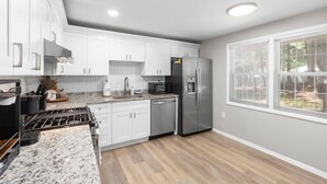 A modern kitchen with white cabinets, stainless steel appliances, and a granite countertop.