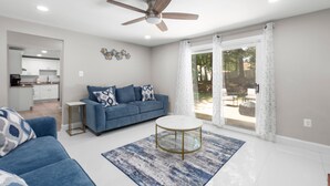 A modern living room with a blue sofa, a round coffee table, and a ceiling fan.
