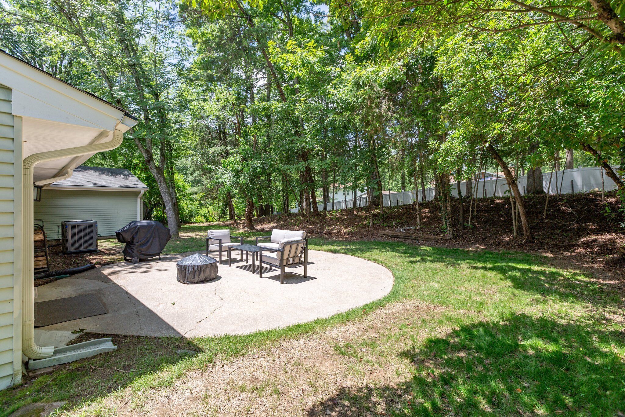 Un jardin avec un patio couvert, un barbecue extérieur et un espace salon.