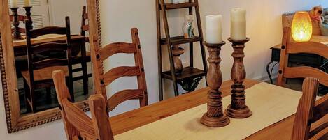 Un comedor con muebles de madera, un espejo, adornos en la pared y una escalera pequeña.