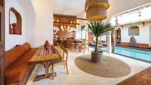 A spacious indoor area with a pool, wooden furniture, and a seating area.