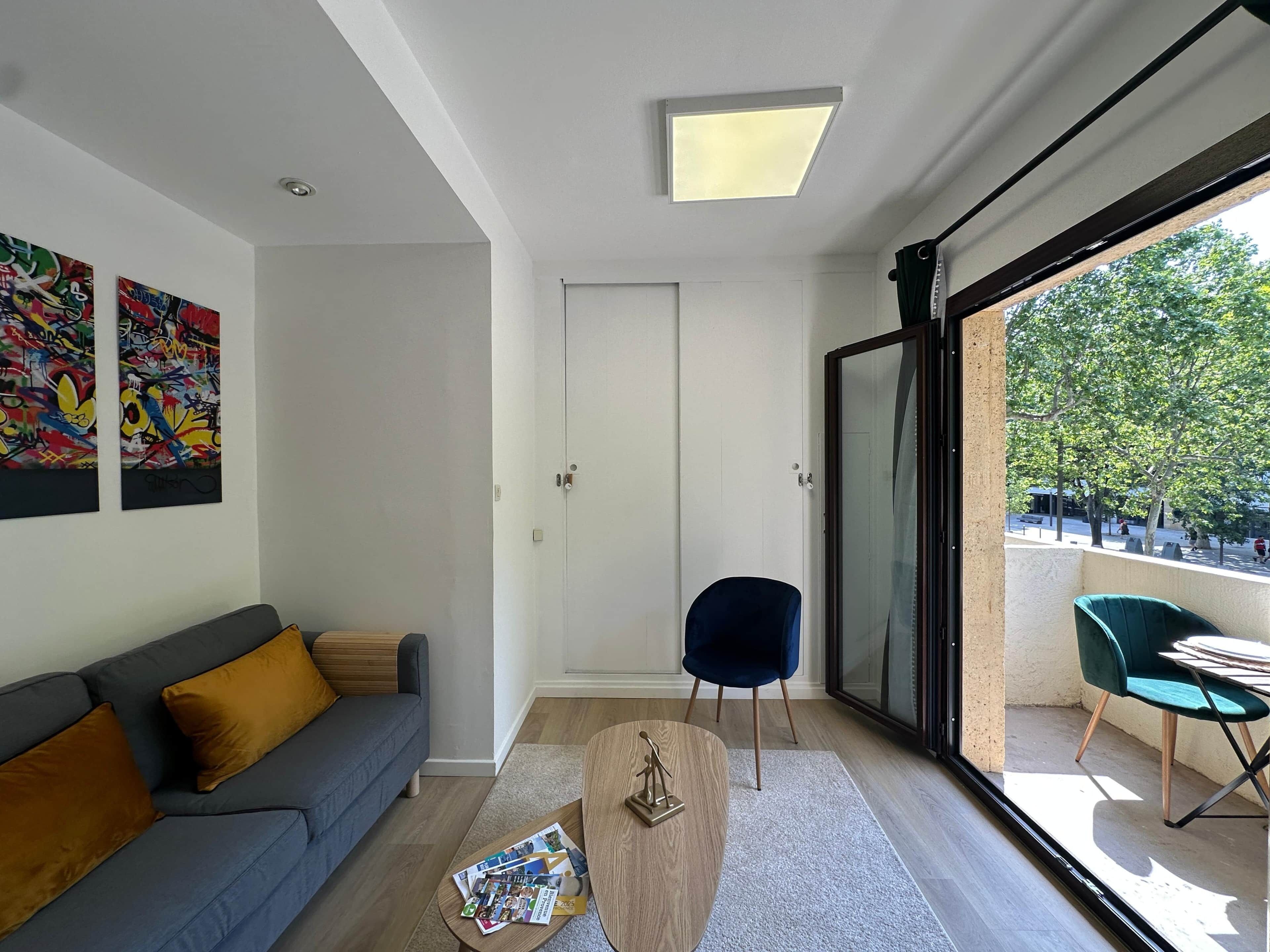 A modern living room with a grey sofa, a coffee table with magazines, and a blue chair.