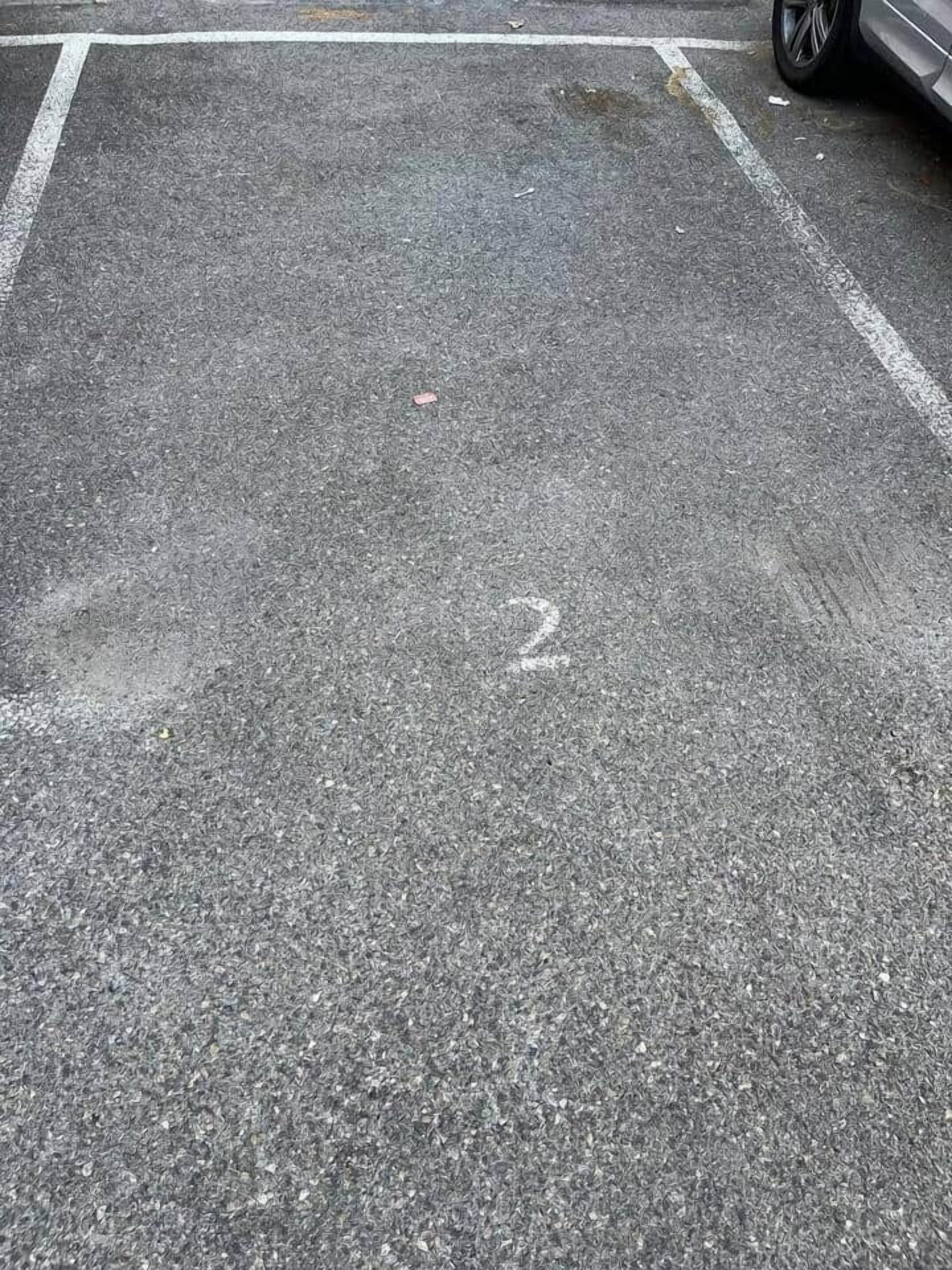 A parking lot with a white line marking and a number '2' on the ground.
