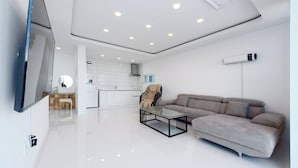 A modern living room with a flat-screen TV, a gray sofa, and a coffee table. - Exit Full Villa (Yeongdeok)