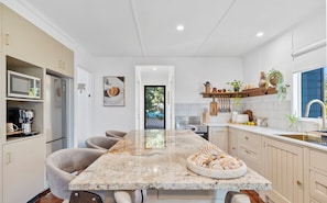 A modern kitchen with a marble countertop, built-in appliances, and a dining area with chairs.
