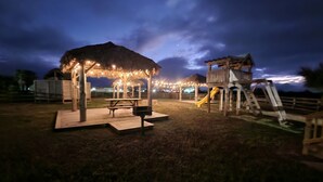 A playground with a picnic table and a covered seating area at dusk. - Coastal Caboose beach container home (Bolivar Peninsula)