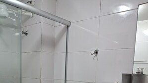 Un baño con cabina de ducha de vidrio, un inodoro con toalla y un lavabo con encimera de granito.
