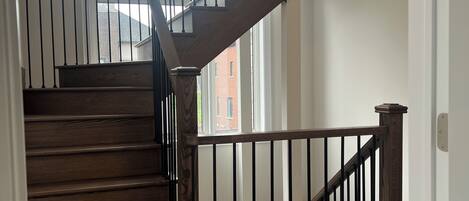 A wooden staircase with black railings, leading to an upper floor.
