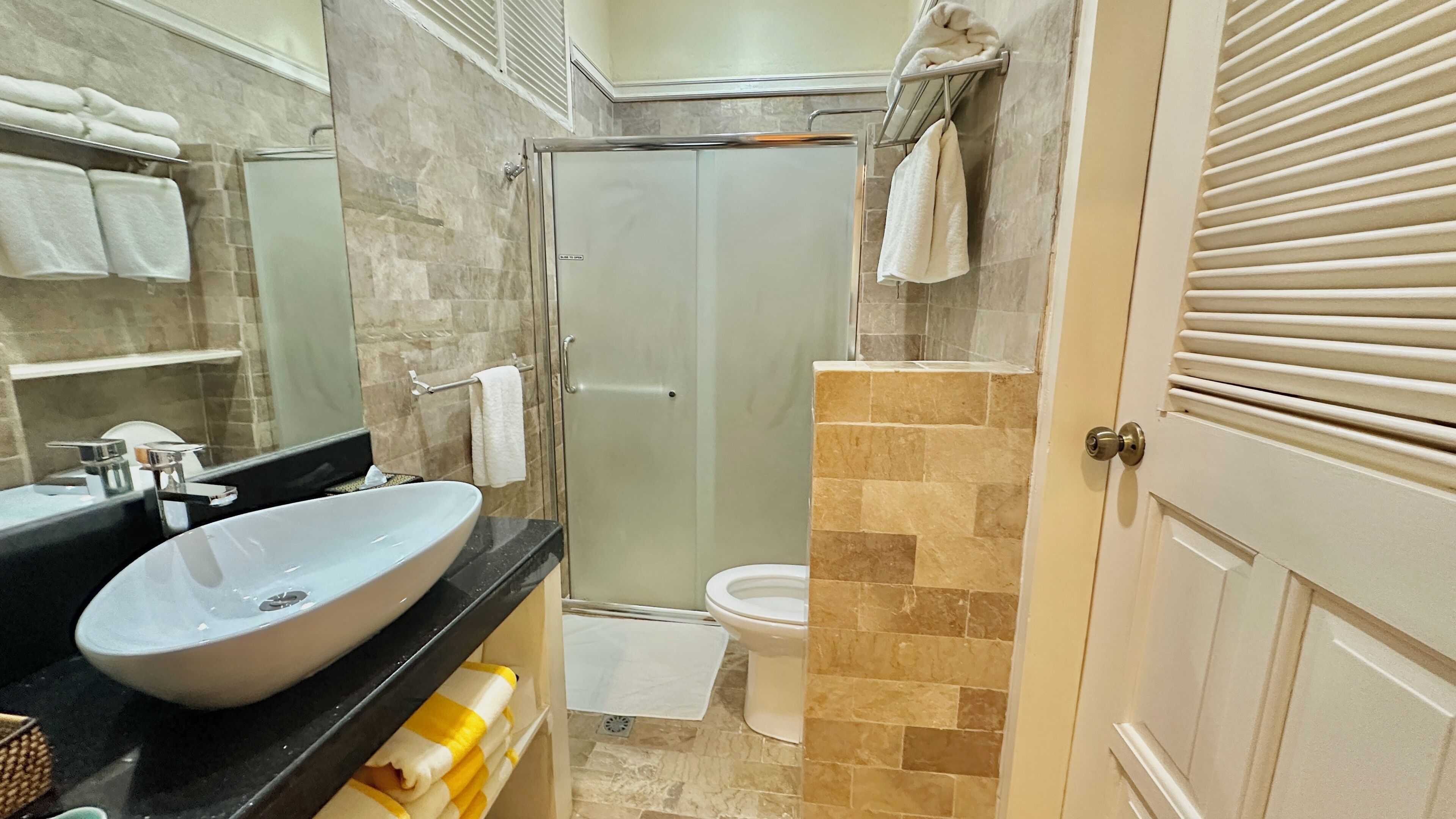 A bathroom with a large sink, toilet, and shower area.