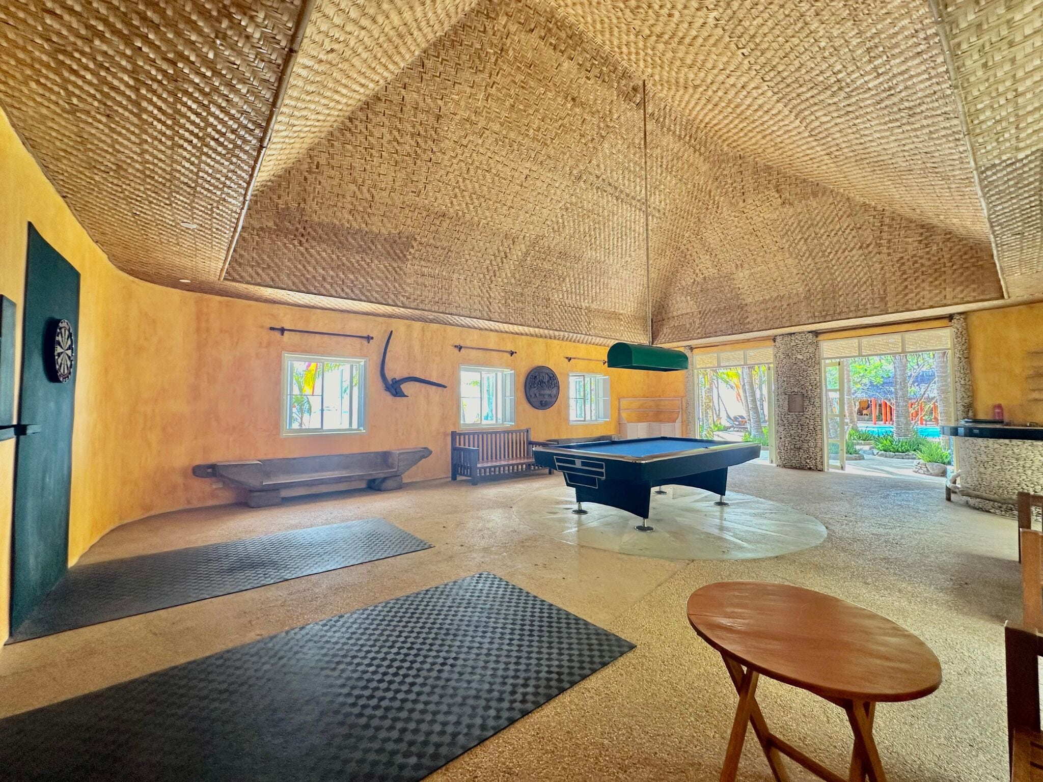 A spacious indoor area with a pool table, exercise mats, and a bench.