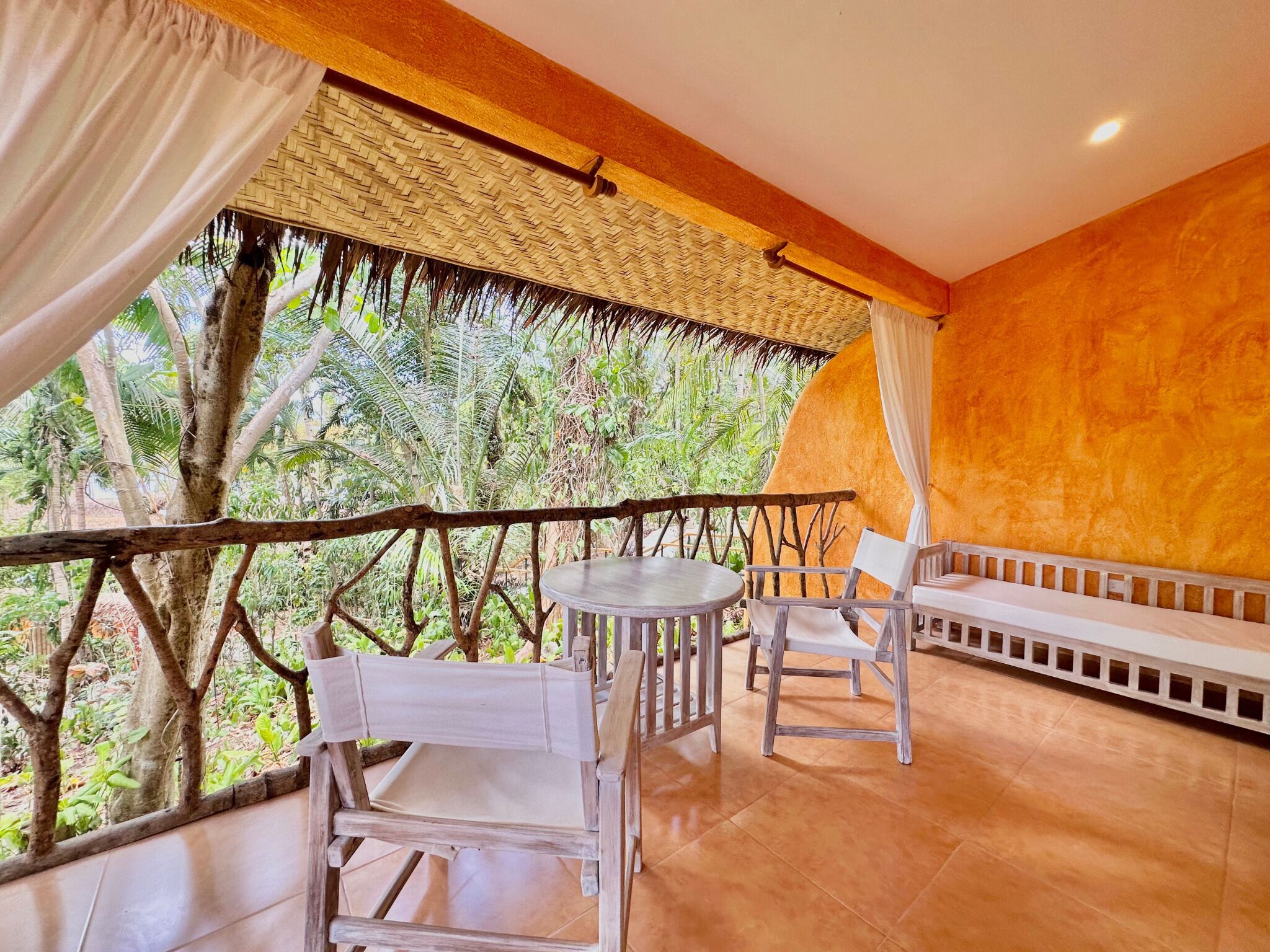 A balcony with a wooden railing, a table, two chairs, and a sofa.