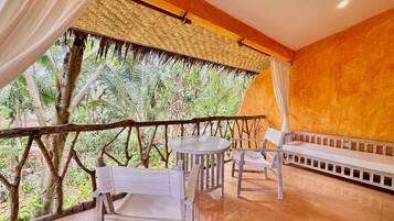 A balcony with a wooden railing, a table, two chairs, and a sofa.