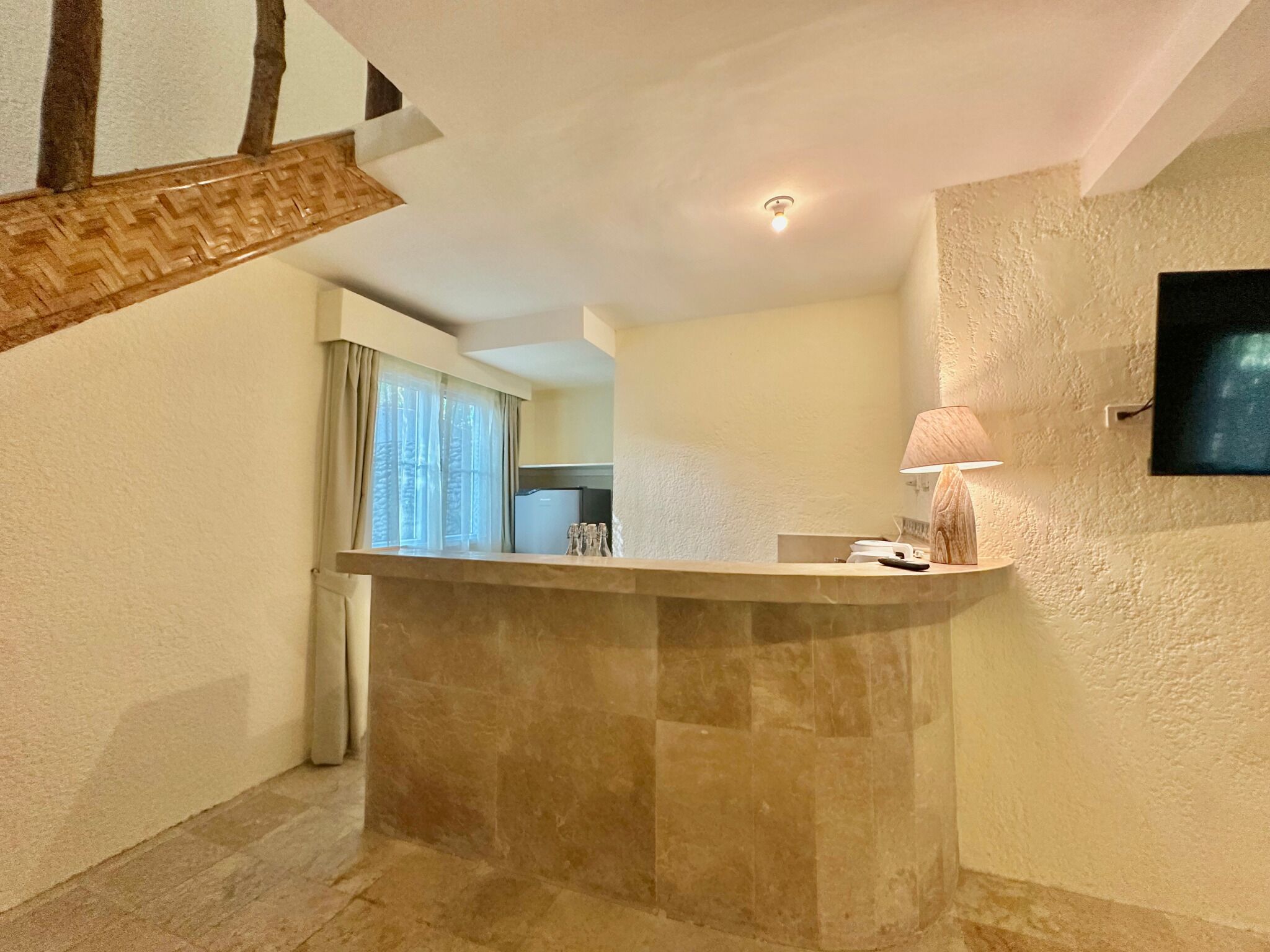 Una cocina moderna con encimera de mármol, estufa integrada y televisor montado en la pared.