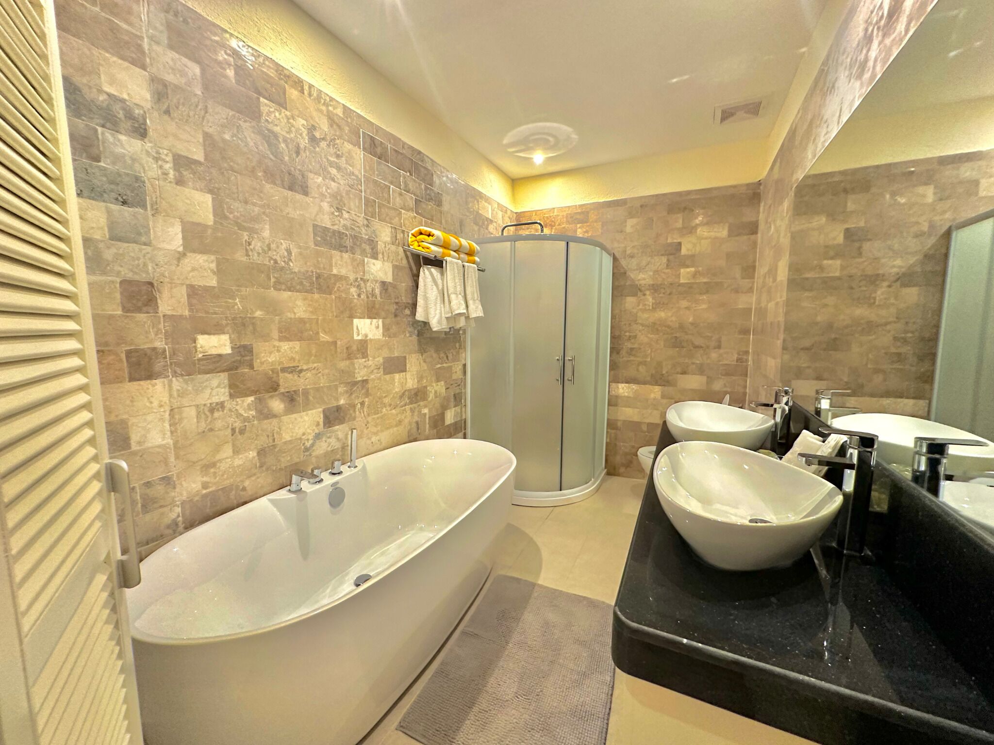 Un baño moderno con una bañera independiente, una ducha a ras de suelo y dos lavamanos.