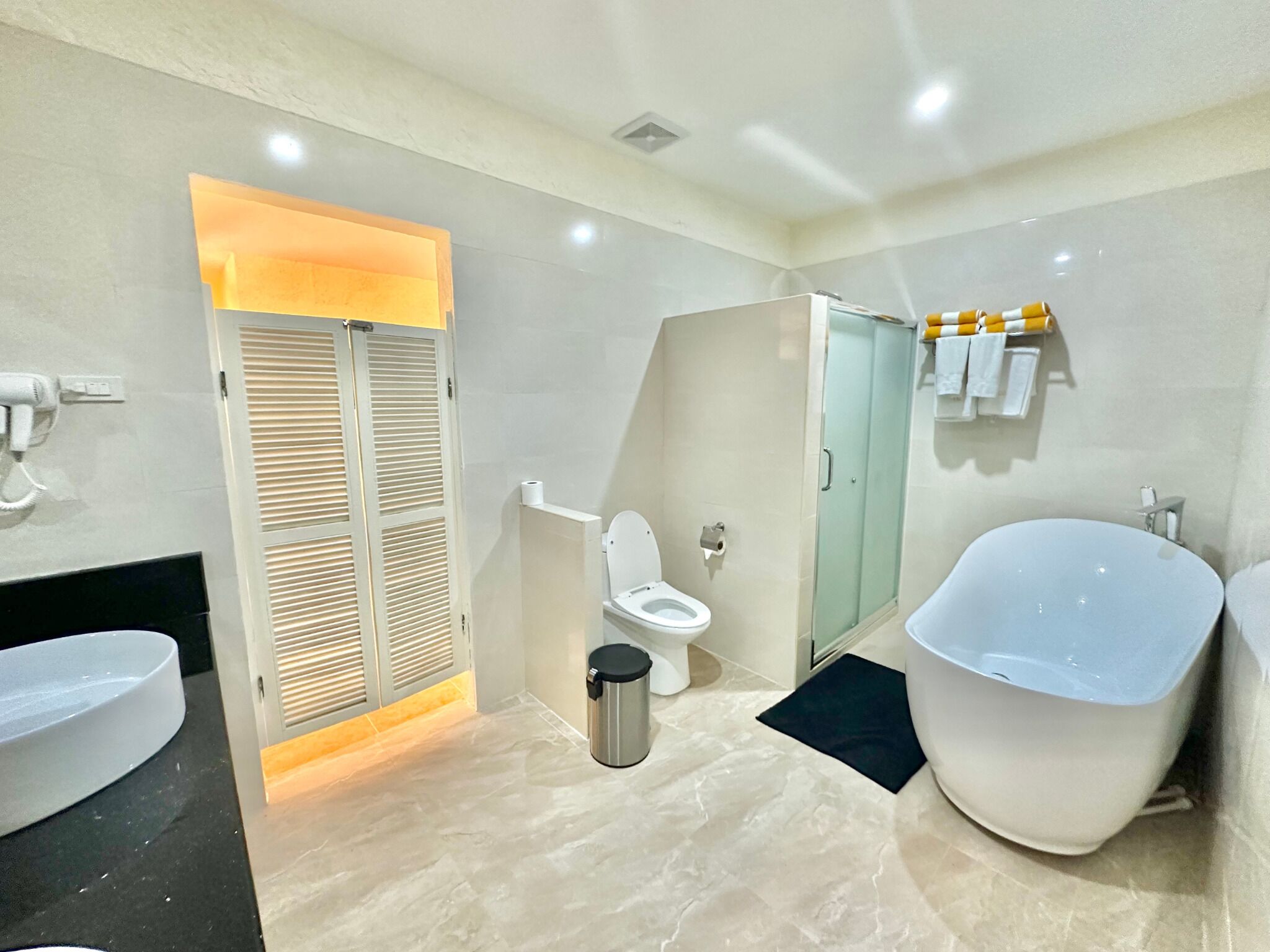 A modern bathroom with a large bathtub, a toilet, a sink, and a shower area.