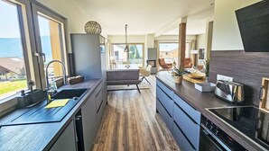 A modern kitchen with a central island, a built-in oven, and a large window overlooking a scenic view.