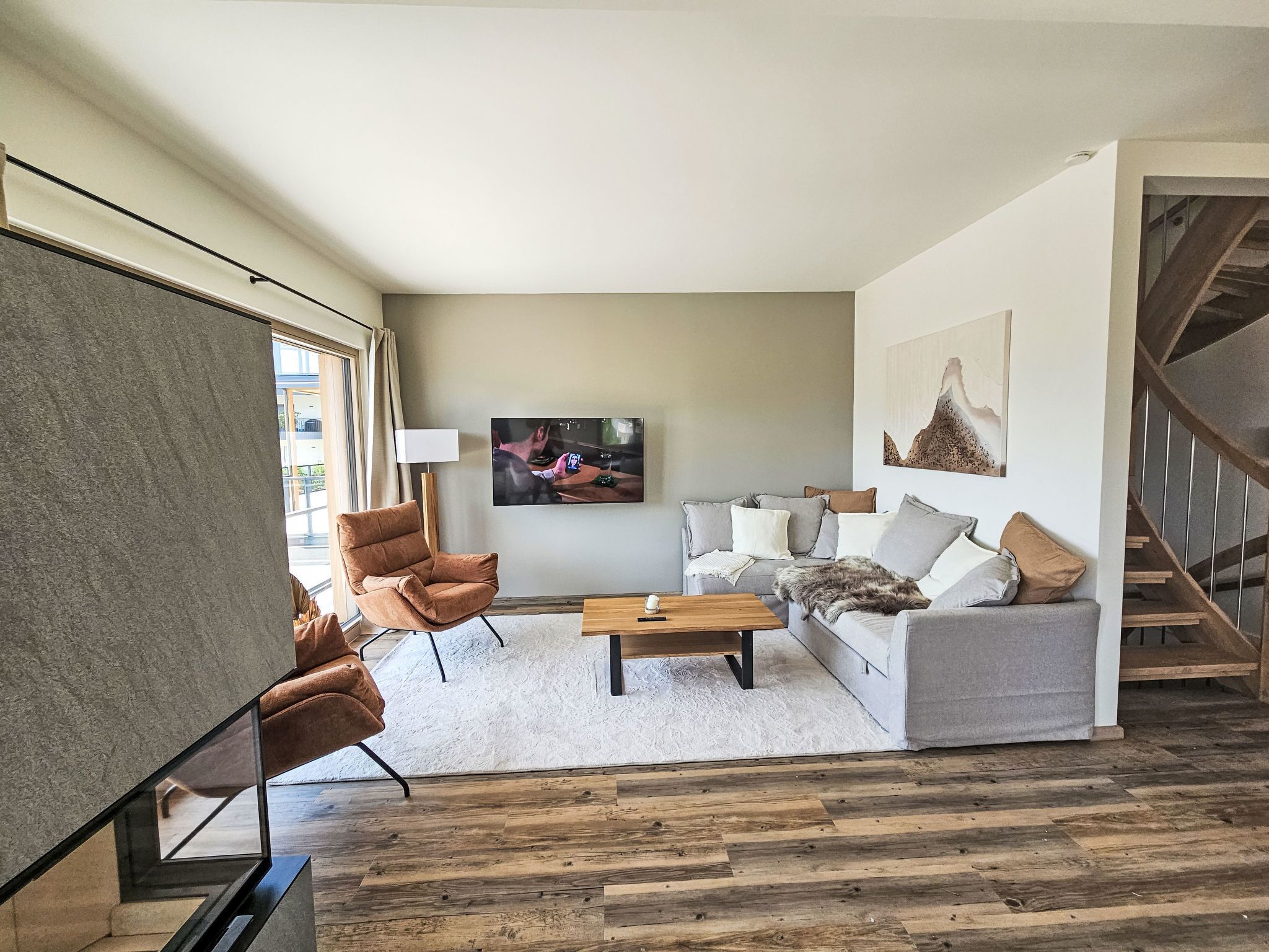 Un salon moderne avec un canapé, des fauteuils, une table basse et un téléviseur.
