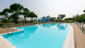 Ein klares Schwimmbecken mit Holzterrasse, umgeben von Bäumen und einem Schild mit der Aufschrift 'impossible beach'.