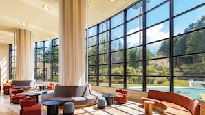 Un'ampia hall con grandi vetrate, una piscina e un'arredamento moderno.