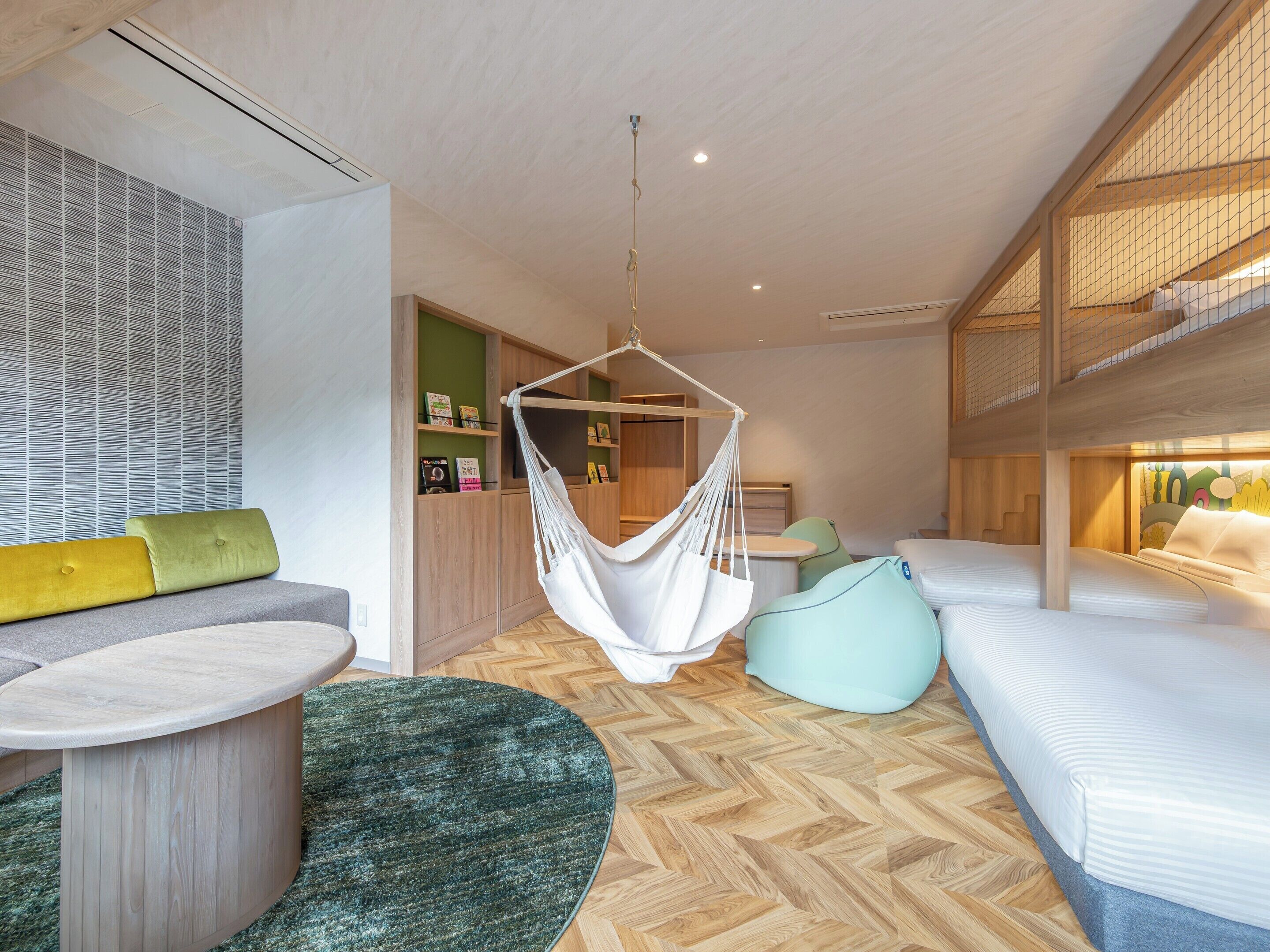 A modern room with a hanging chair, a sofa, a bed, and a herringbone-patterned floor.