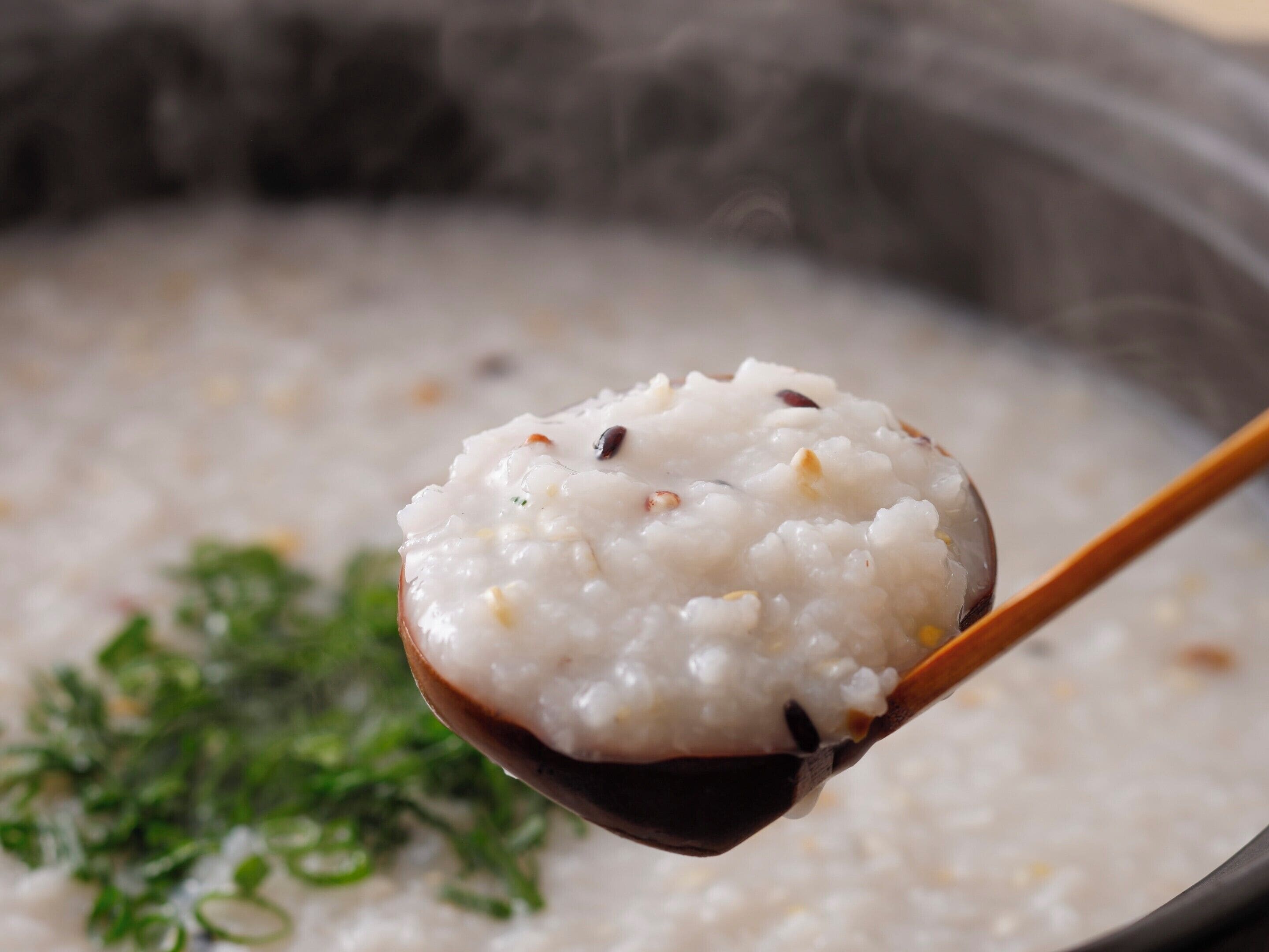 A close-up of a spoonful of rice porridge with visible grains and herbs.