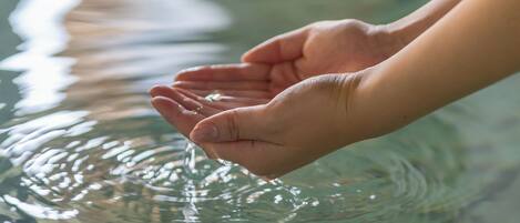 A pair of hands cupped over a body of water, creating ripples.