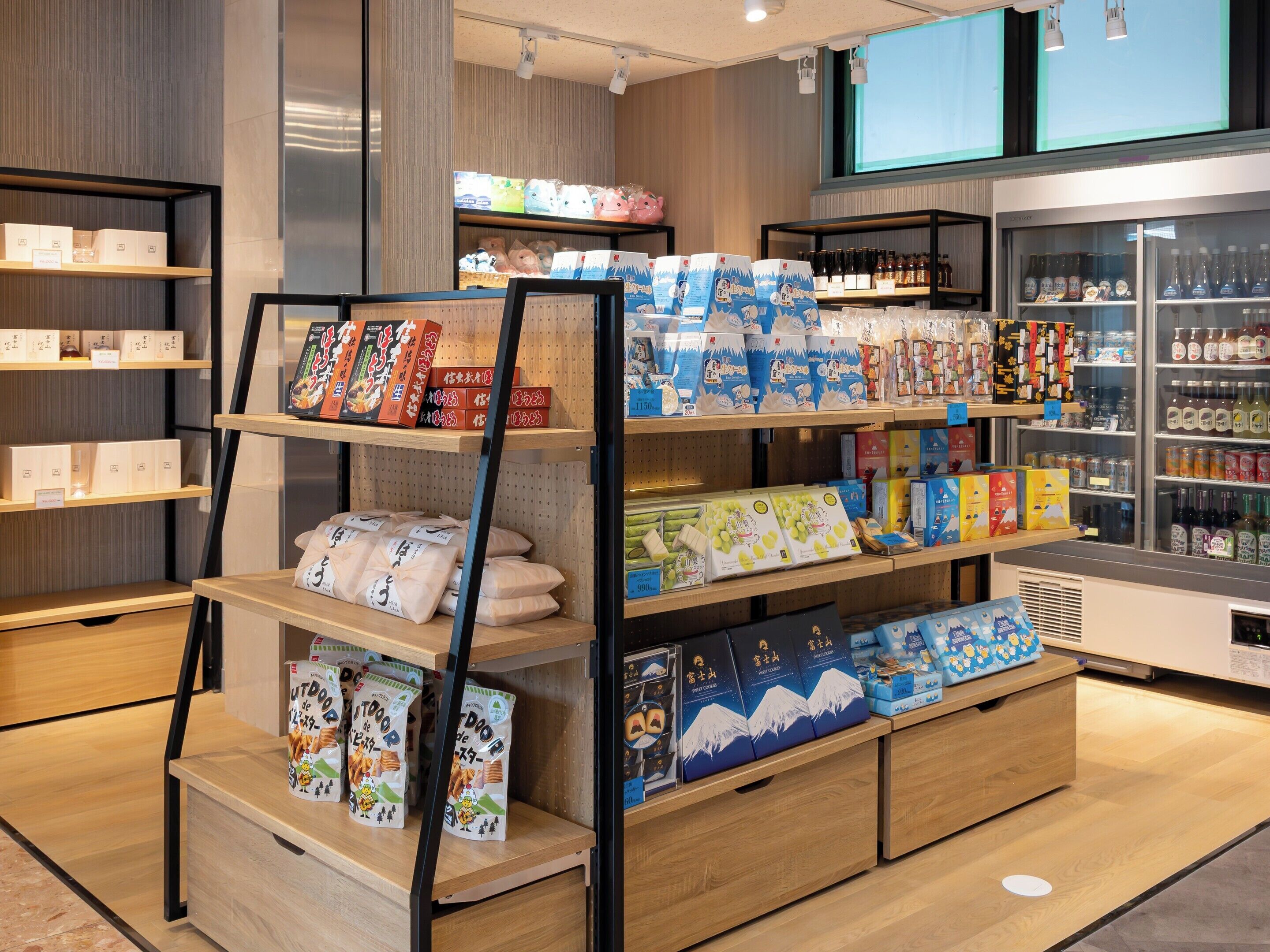 Ein Verkaufsregal mit verschiedenen verpackten Waren, darunter Snacks und Getränke, die auf Regalen und in einer Kühlvitrine angeordnet sind.