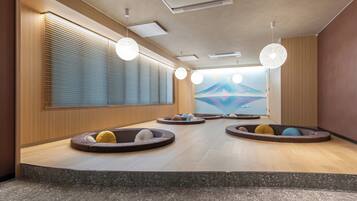 A modern interior with a central seating area, a large window with blinds, and a wall-mounted air conditioning unit.