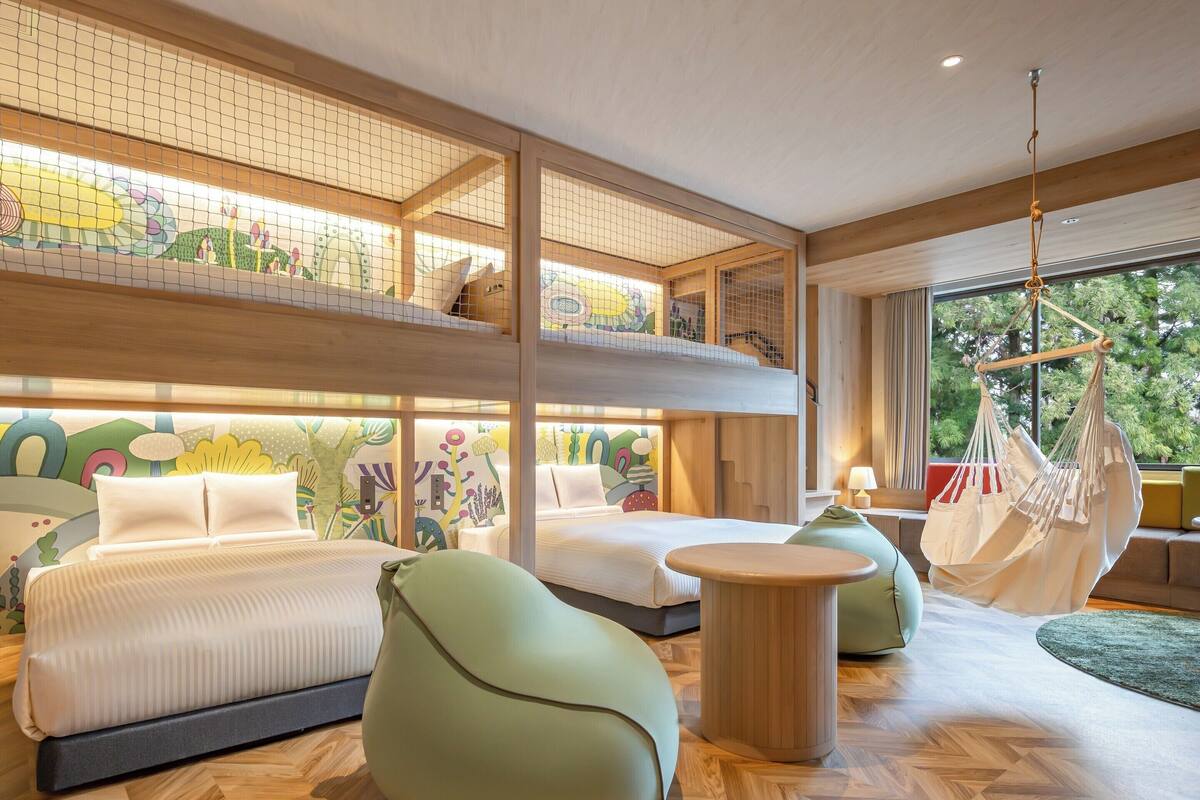 A multi-level bedroom with bunk beds, a hanging chair, and a round table.