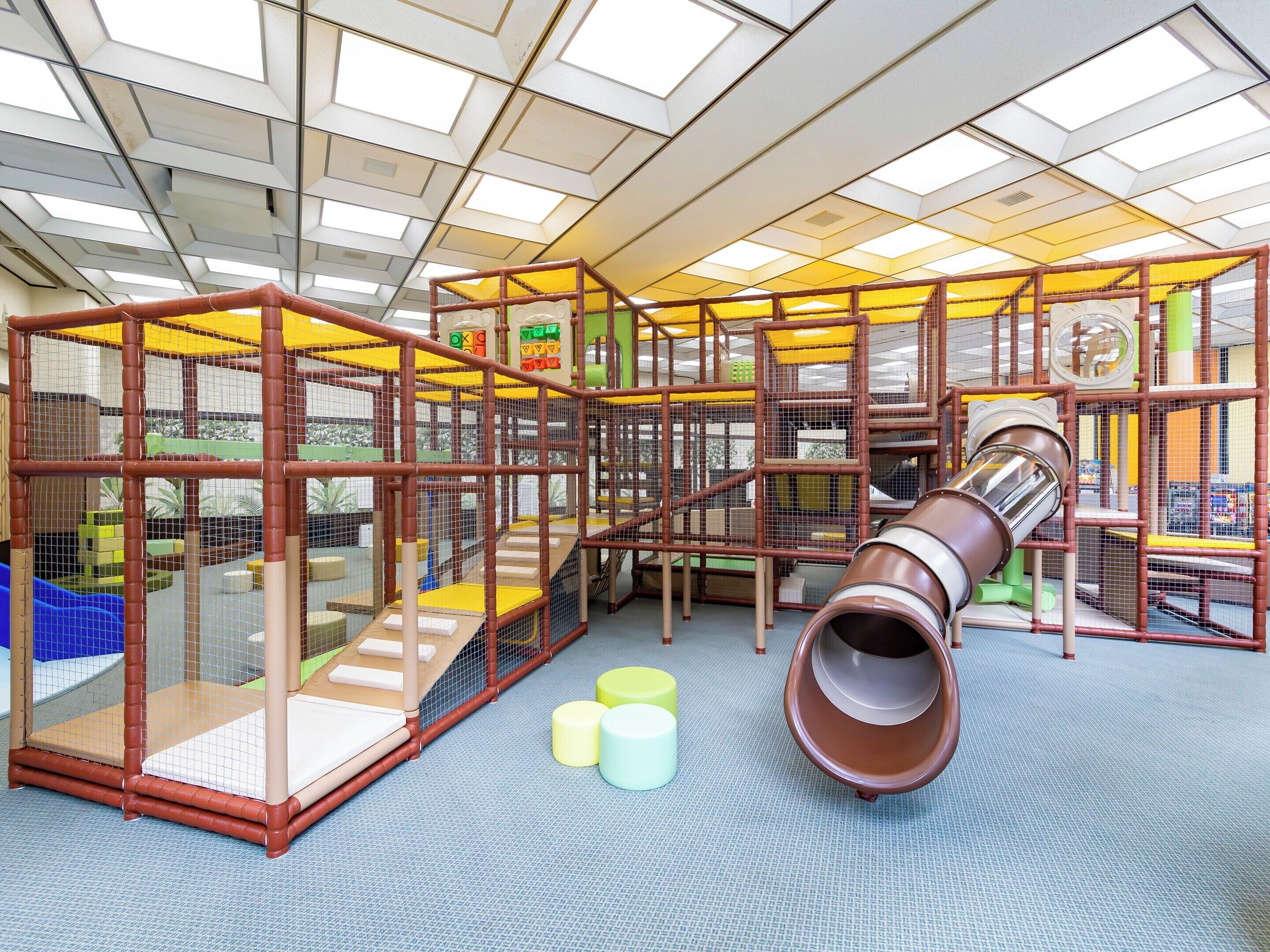 A play area with a slide, climbing structures, and padded seating.