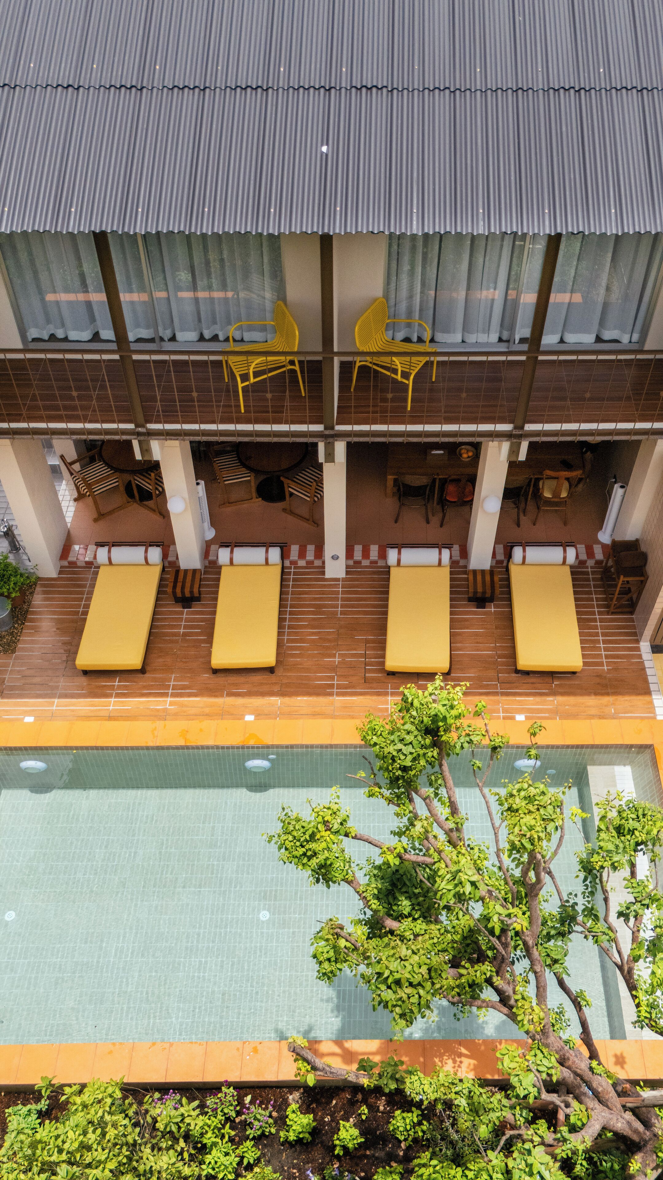 A rooftop pool area with yellow lounge chairs and a view of the pool.