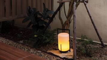 A lantern-style light fixture mounted on a wooden stand in a garden setting.