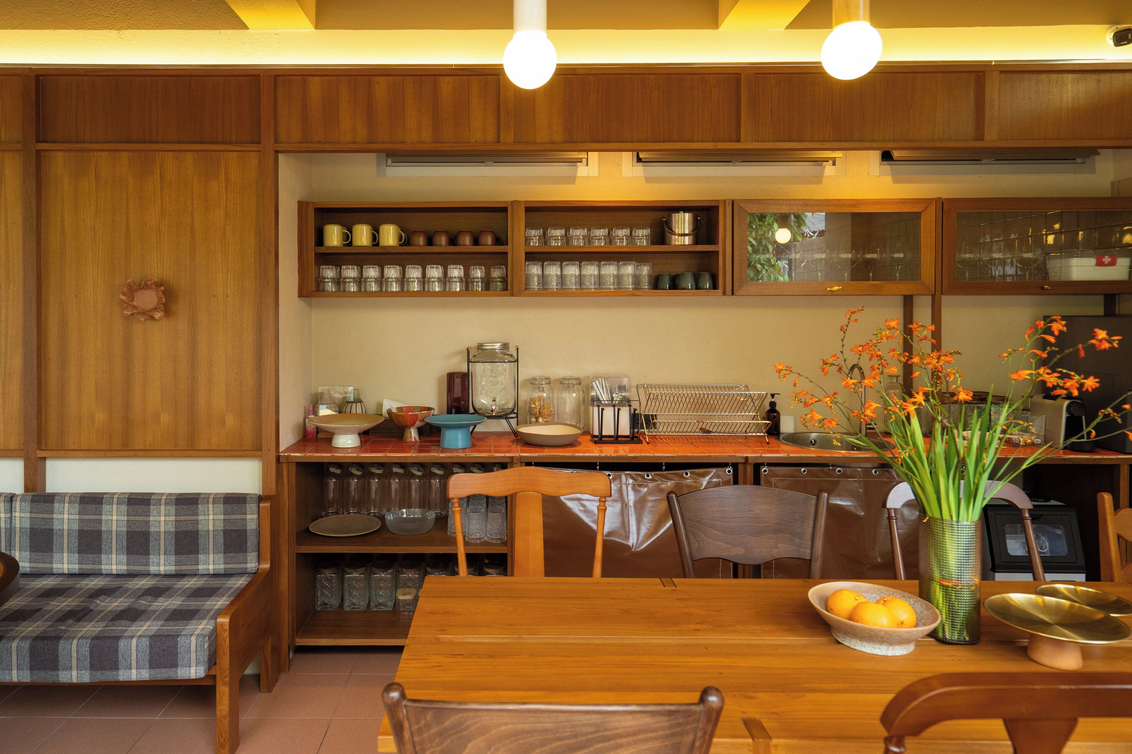 A cozy kitchen with wooden cabinets, a dining table, and a bench.
