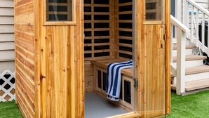 A wooden sauna structure with a bench and a towel, set on artificial grass. - 2x Home Entertainment Oasis. Sauna, Hot Tub, Games (Galveston)