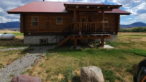 A rustic log cabin with a red roof, a porch with a railing, and a sign that reads "HAPPENTRAILS." - Charming 2-bedroom cabin in Emigrant with Beautiful Views (Emigrant)