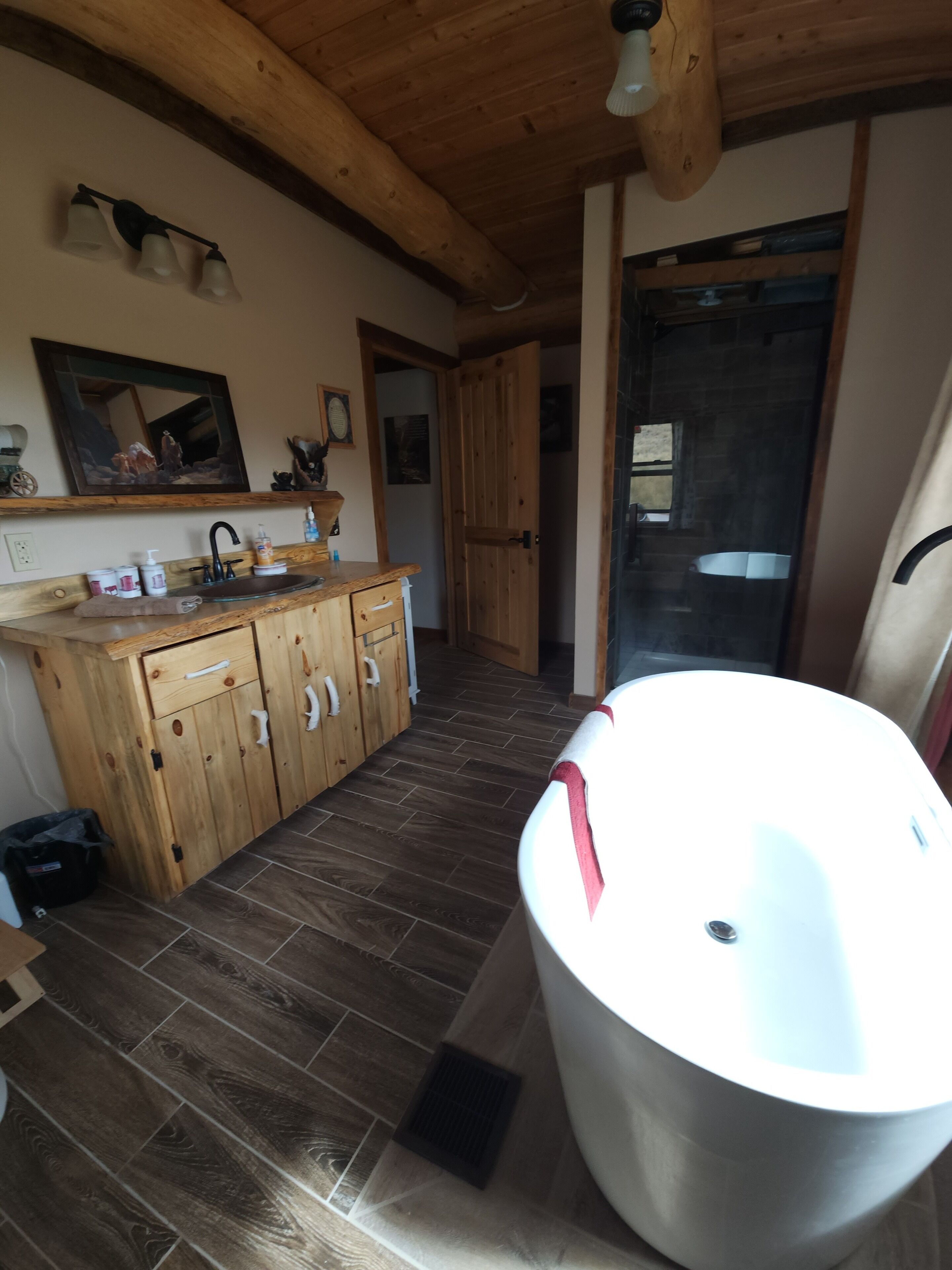 A bathroom with a wooden vanity, a large bathtub, and a mirror above the sink.