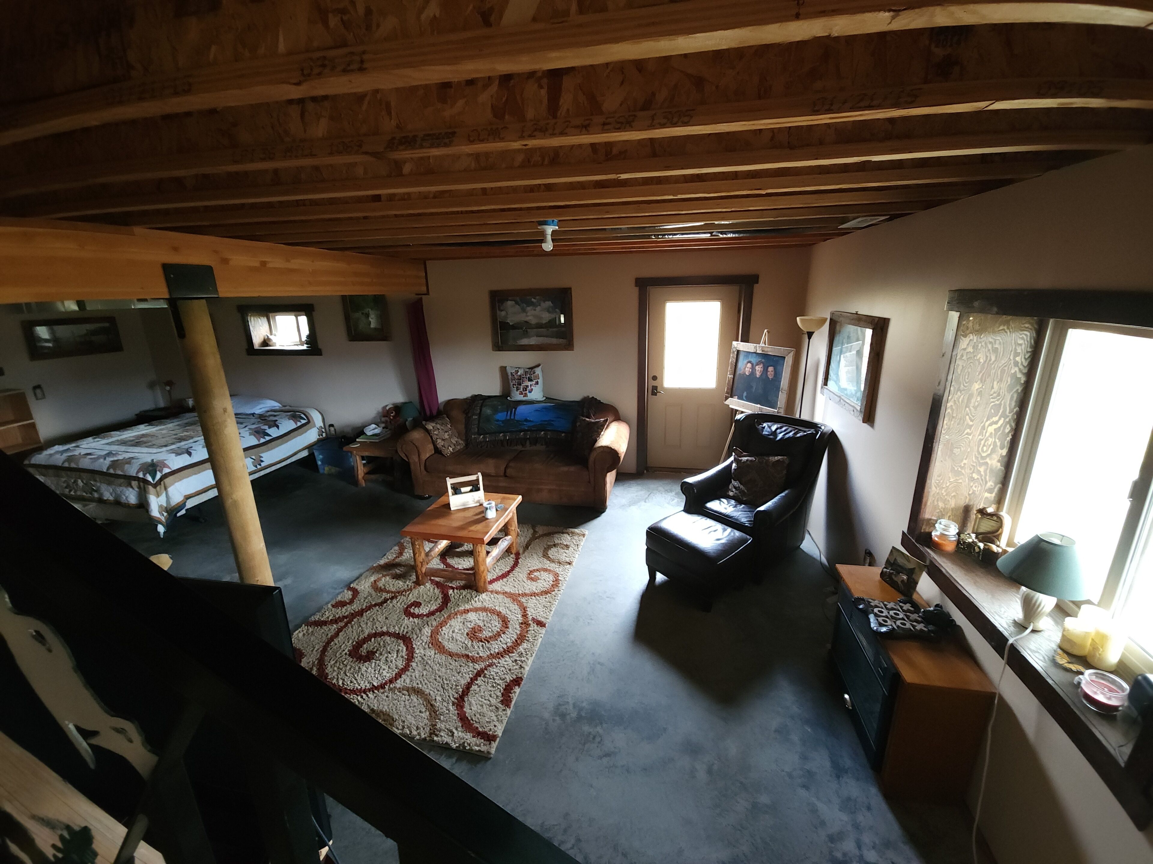 A cozy attic room with a bed, a sofa, a chair, and a small table.